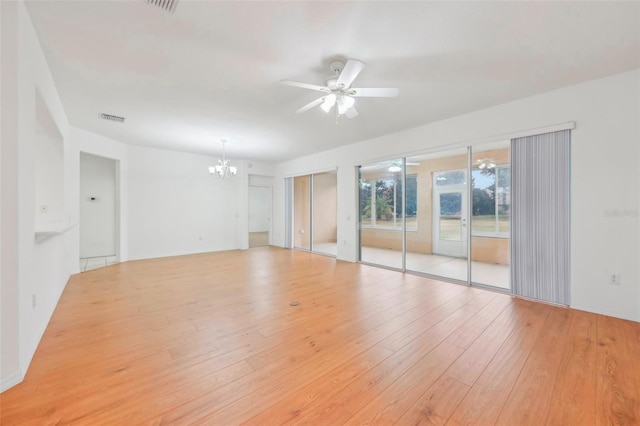 spare room featuring hardwood / wood-style flooring, visible vents, and ceiling fan with notable chandelier