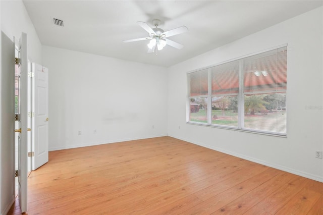 spare room featuring a ceiling fan, light wood-type flooring, visible vents, and baseboards