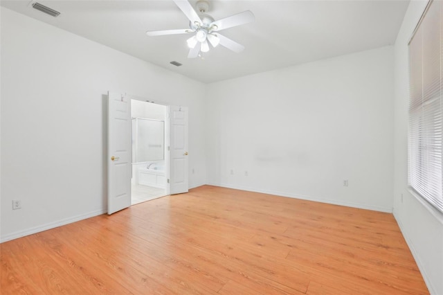 empty room featuring a ceiling fan, light wood-type flooring, visible vents, and baseboards