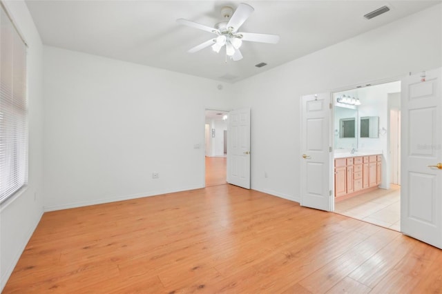 unfurnished bedroom with ensuite bathroom, light wood finished floors, visible vents, and baseboards