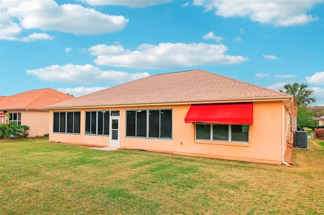 rear view of property featuring stucco siding, a shingled roof, central AC unit, and a yard