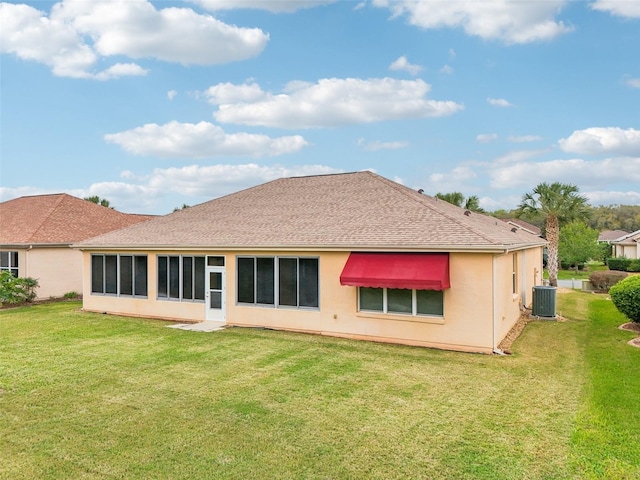 back of property with central AC, a yard, a shingled roof, and stucco siding