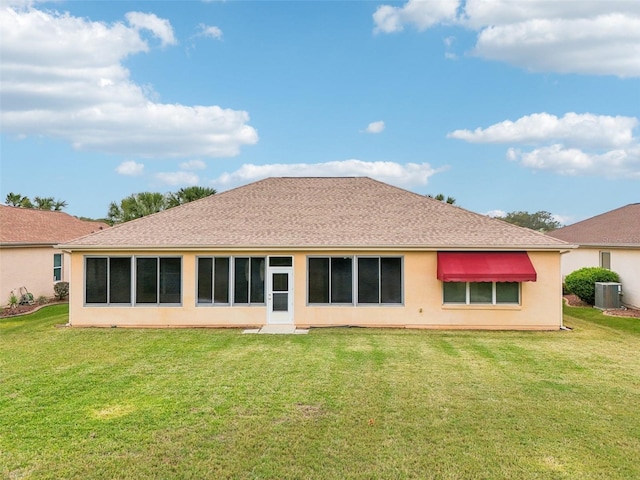 back of property with a yard, a shingled roof, central AC unit, and stucco siding