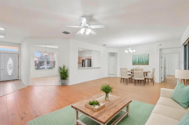 living room featuring ceiling fan with notable chandelier, wood finished floors, and visible vents