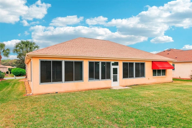 rear view of house with a shingled roof, a lawn, and stucco siding