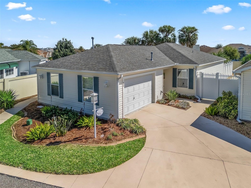 ranch-style house with a shingled roof, concrete driveway, fence, and an attached garage