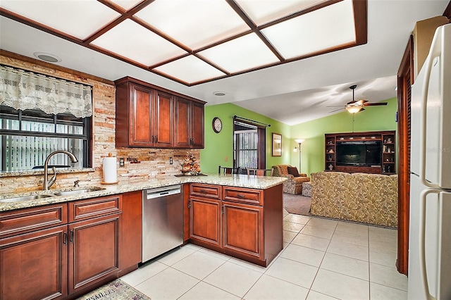 kitchen featuring light tile patterned floors, dishwasher, freestanding refrigerator, a peninsula, and a sink