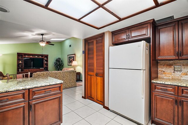 kitchen with light tile patterned floors, decorative backsplash, light stone counters, open floor plan, and freestanding refrigerator