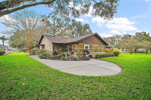 exterior space featuring brick siding, a lawn, and a sunroom