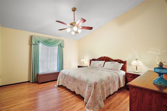 bedroom with a ceiling fan, lofted ceiling, light wood-style flooring, and baseboards