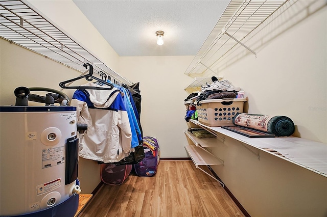 walk in closet featuring water heater and wood finished floors