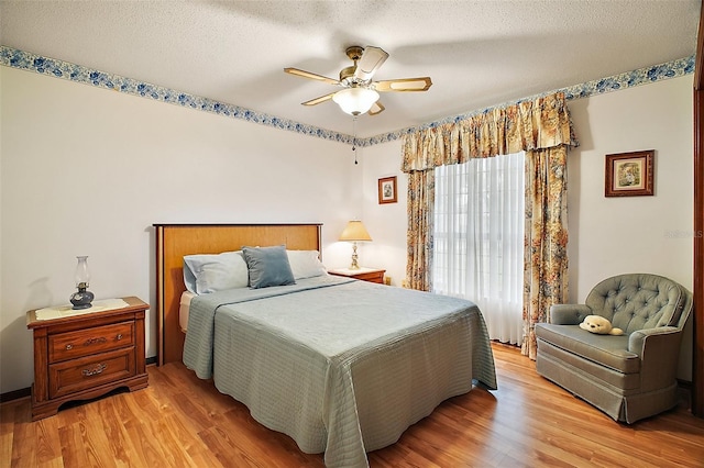 bedroom with light wood-style floors, ceiling fan, and a textured ceiling