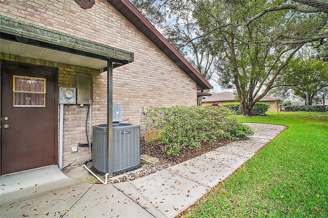 view of home's exterior featuring a yard, central AC, and brick siding