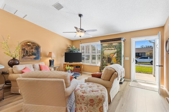 living room featuring vaulted ceiling, a healthy amount of sunlight, visible vents, and light wood-style floors