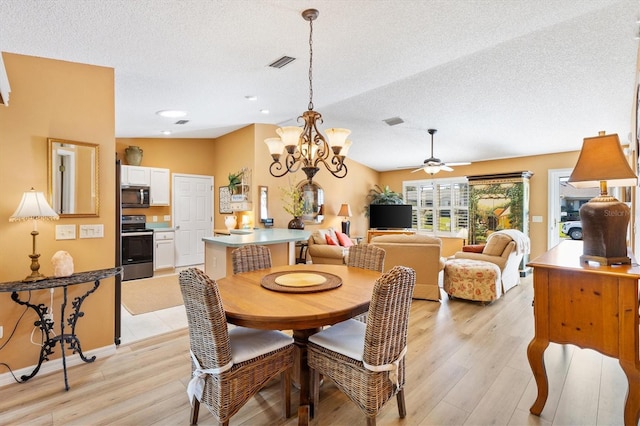 dining room featuring light wood-type flooring, visible vents, a textured ceiling, and ceiling fan with notable chandelier