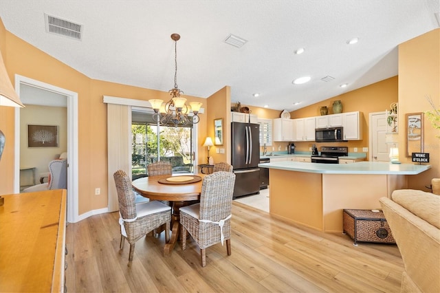 kitchen with lofted ceiling, a peninsula, appliances with stainless steel finishes, and visible vents