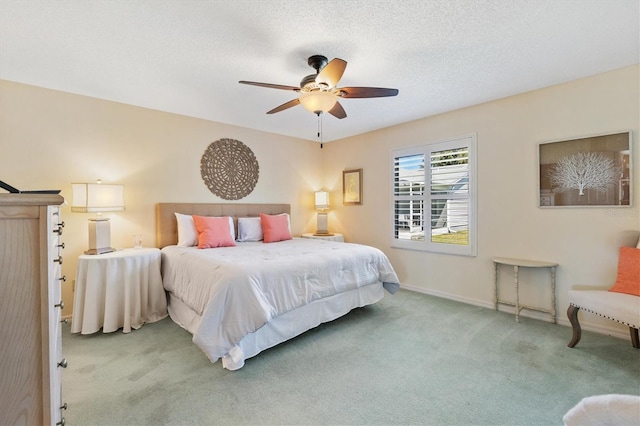 carpeted bedroom with a textured ceiling, a ceiling fan, and baseboards