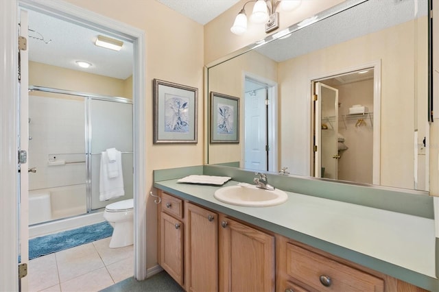 bathroom featuring toilet, a shower stall, a textured ceiling, vanity, and tile patterned flooring