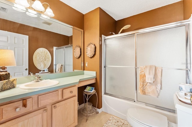 bathroom featuring toilet, tile patterned flooring, combined bath / shower with glass door, a textured ceiling, and vanity