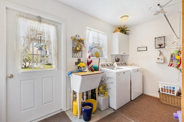 laundry area with a textured ceiling, a wealth of natural light, washer and clothes dryer, and cabinet space