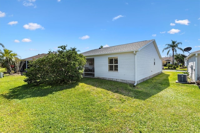 rear view of property featuring central AC unit, a lawn, and a sunroom