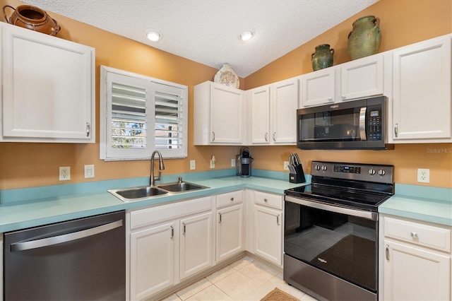 kitchen with light tile patterned floors, light countertops, appliances with stainless steel finishes, a sink, and a textured ceiling