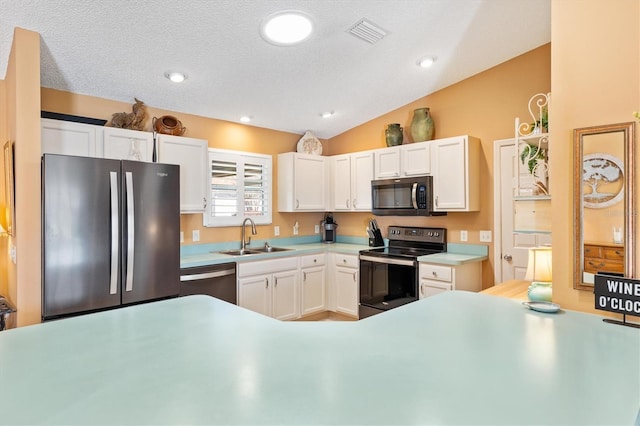 kitchen with lofted ceiling, white cabinetry, stainless steel appliances, and a sink