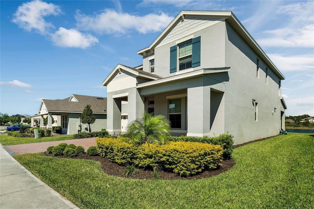 view of side of property featuring decorative driveway, a lawn, and stucco siding