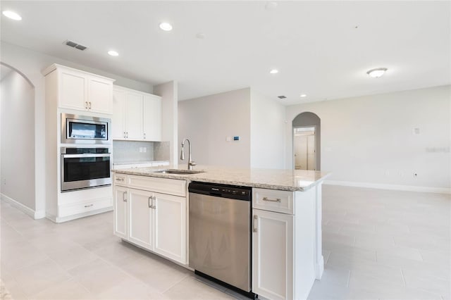 kitchen featuring arched walkways, tasteful backsplash, visible vents, appliances with stainless steel finishes, and a sink