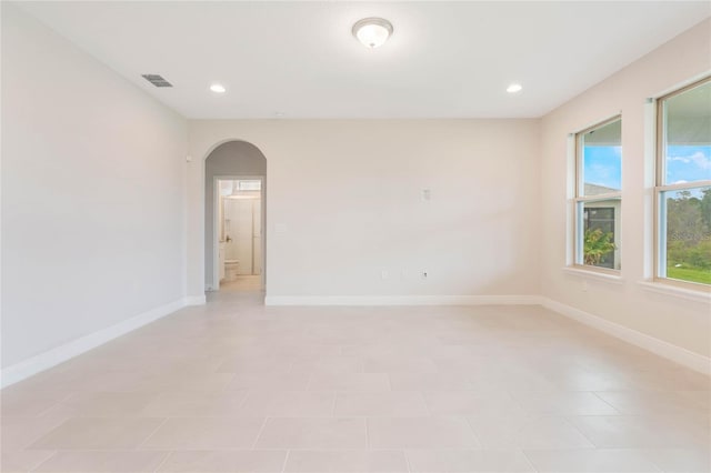 unfurnished room featuring baseboards, visible vents, arched walkways, and recessed lighting