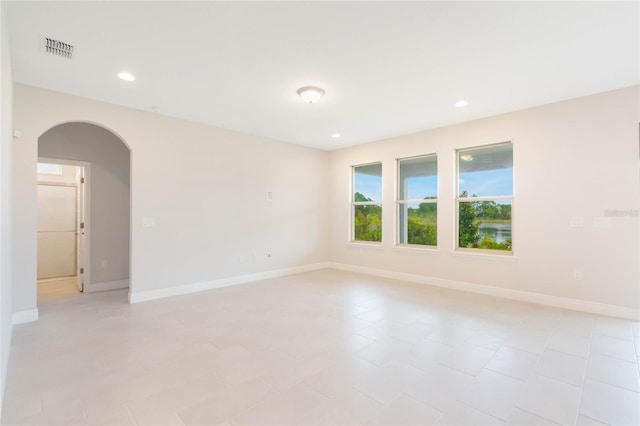 unfurnished room with baseboards, visible vents, arched walkways, and recessed lighting