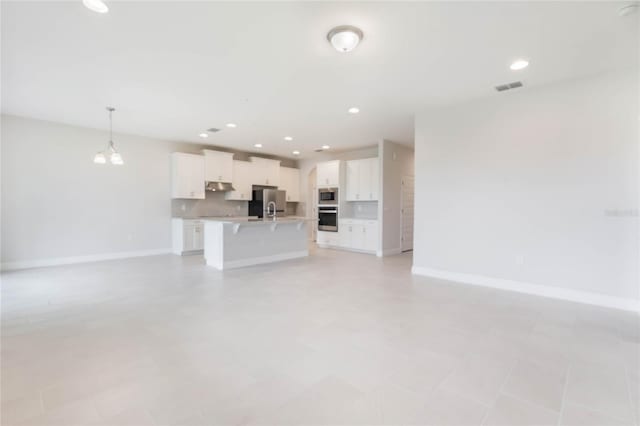 unfurnished living room with baseboards, visible vents, and recessed lighting