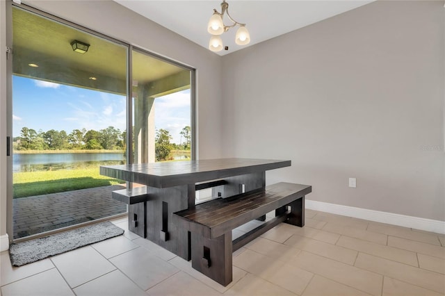 dining space featuring a water view, light tile patterned floors, baseboards, and a notable chandelier