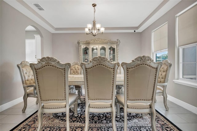 dining area with light tile patterned floors, arched walkways, a chandelier, and visible vents