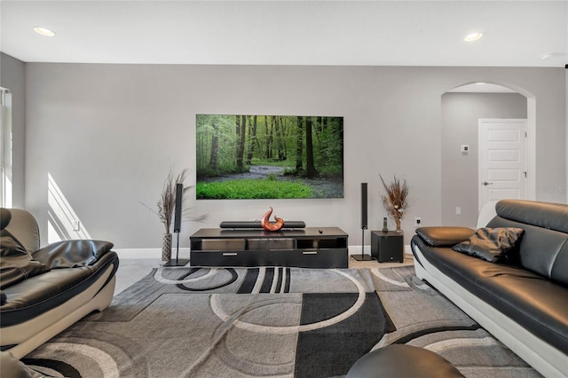 carpeted living room featuring arched walkways, baseboards, and recessed lighting