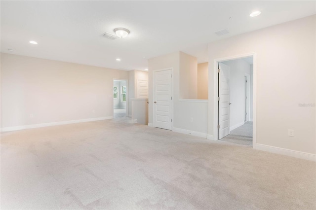 spare room with recessed lighting, light carpet, visible vents, and baseboards