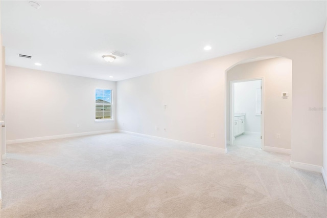 unfurnished room with light carpet, baseboards, visible vents, arched walkways, and recessed lighting