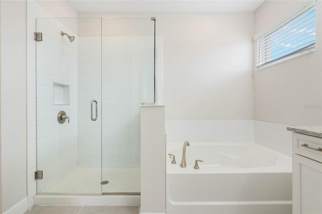 bathroom featuring a stall shower, a garden tub, and vanity