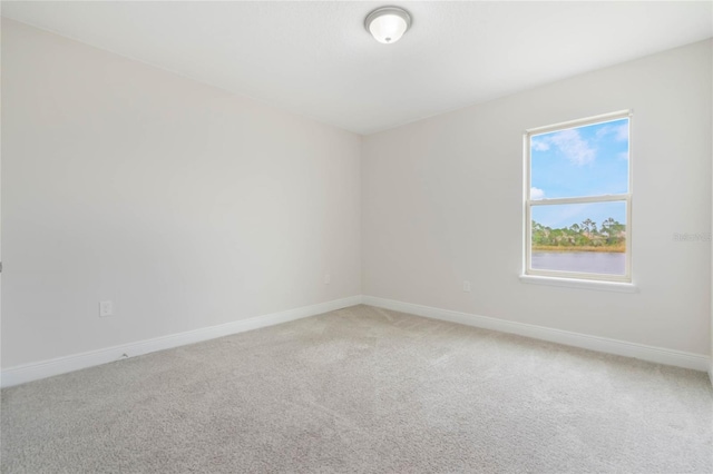 spare room featuring baseboards and light colored carpet