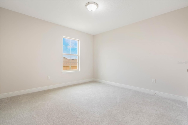 empty room featuring light carpet and baseboards