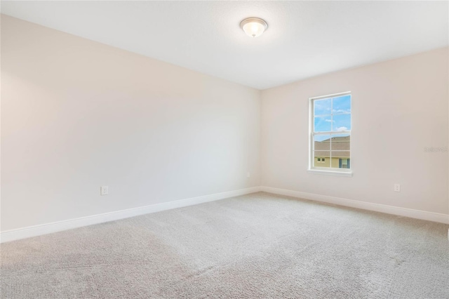 empty room featuring light carpet and baseboards