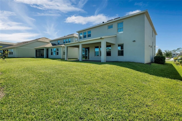 back of property featuring a lawn and stucco siding