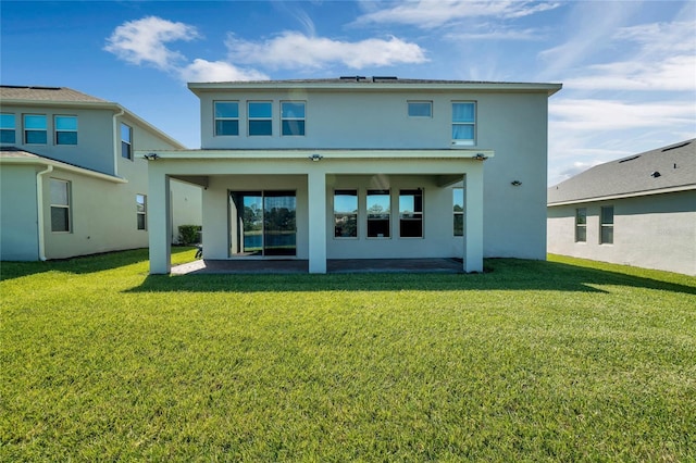 rear view of property featuring a patio area, a lawn, and stucco siding