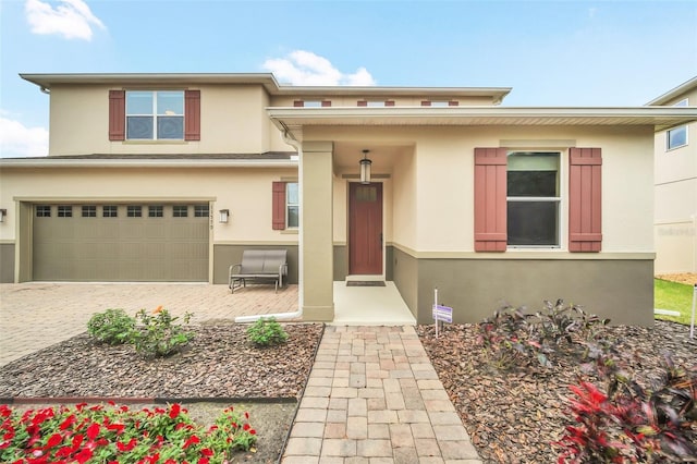 view of front of property featuring an attached garage, decorative driveway, and stucco siding