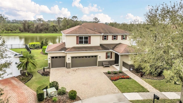 view of front of property with a front lawn, decorative driveway, a water view, and stucco siding