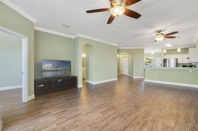 living area with arched walkways, light wood-style flooring, visible vents, baseboards, and crown molding