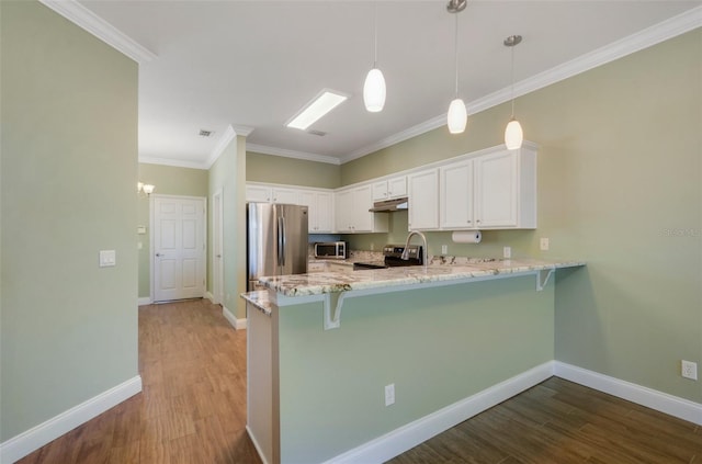 kitchen with light stone counters, a peninsula, wood finished floors, white cabinetry, and appliances with stainless steel finishes