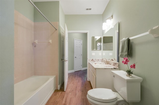 bathroom featuring visible vents, toilet, shower / tub combination, wood finished floors, and vanity