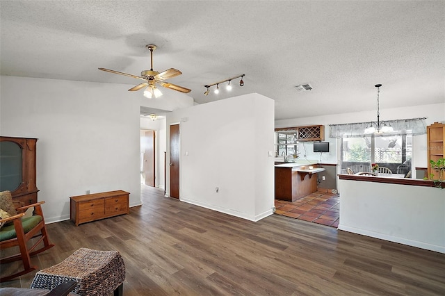 living room with a textured ceiling, ceiling fan with notable chandelier, dark wood-style flooring, visible vents, and baseboards