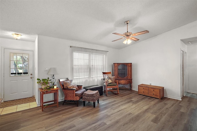 living area featuring lofted ceiling, ceiling fan, a textured ceiling, and wood finished floors